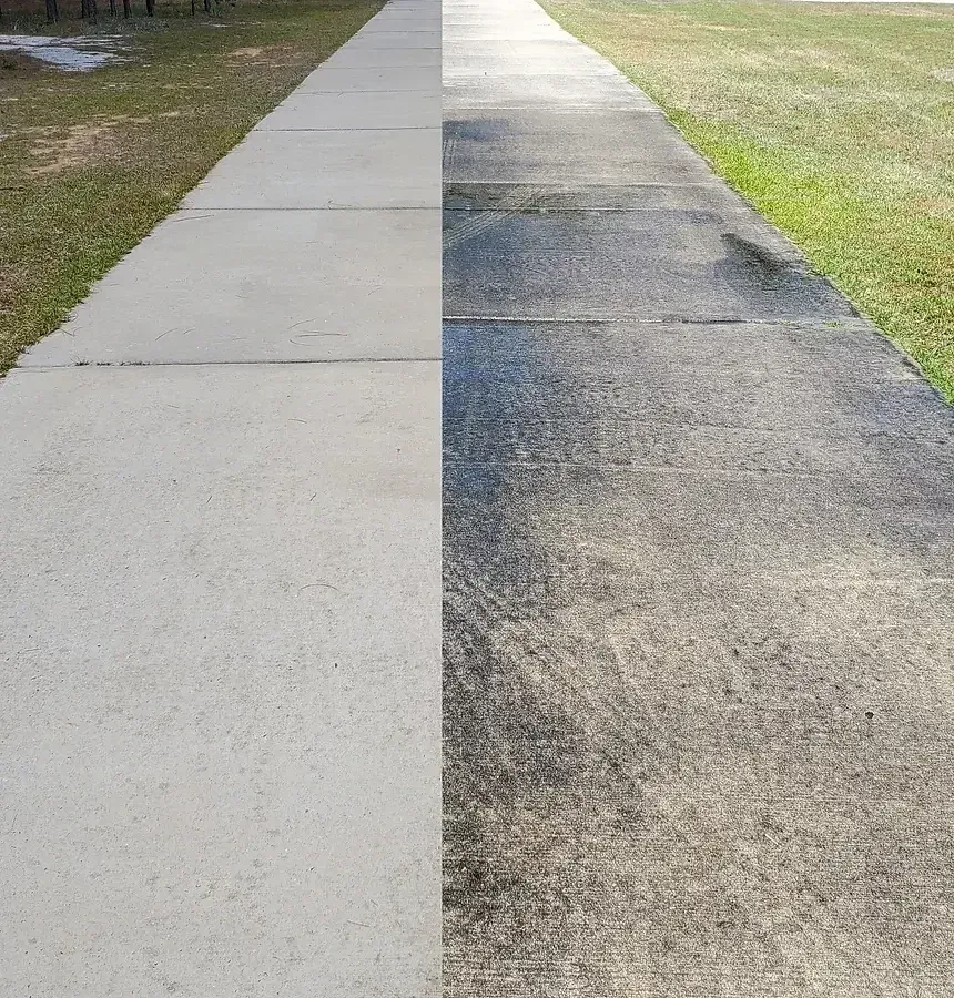Concrete driveway with visible dark organic staining beside a professionally cleaned section with an even, uniform finish